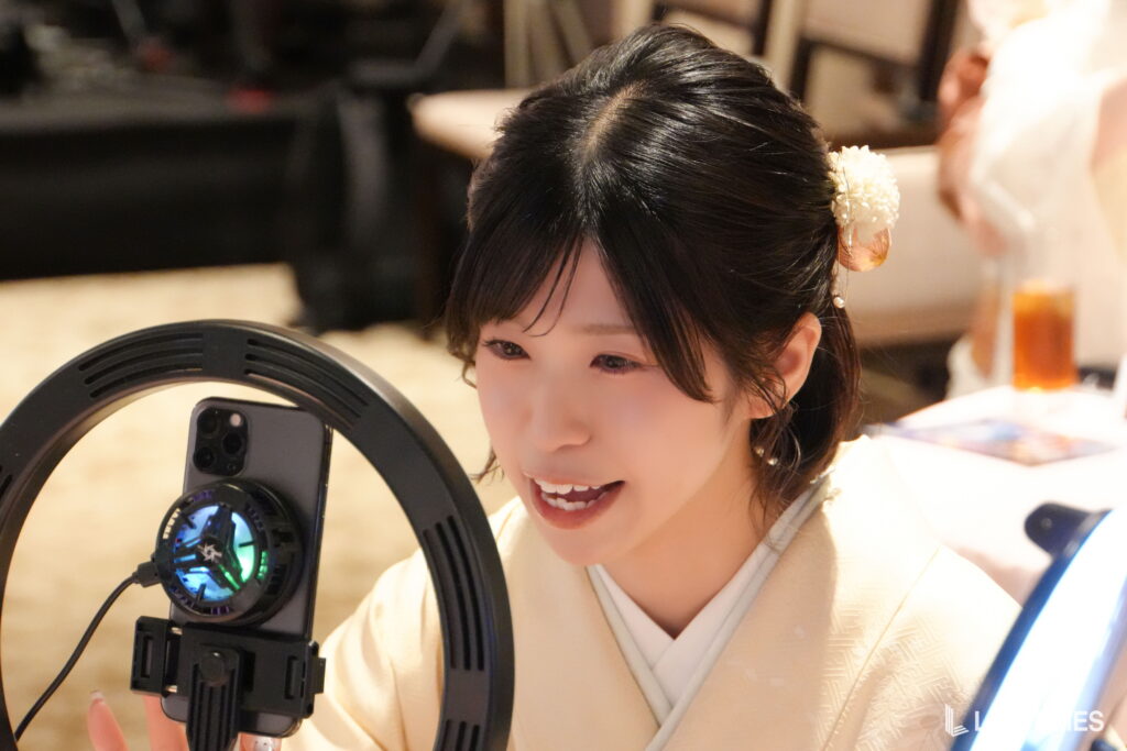 Young woman in a light kimono smiles while looking at a large circular device with a blue-lit display in front of her.