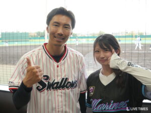 〈インタビュー〉ASTERISK所属・あくあ、「TikTok ROYALE BASEBALL」でウグイス嬢に挑戦 Two baseball players pose for a photo in front of a fence at a field, the man in a white pinstripe jersey and the woman in a dark jersey giving thumbs up.