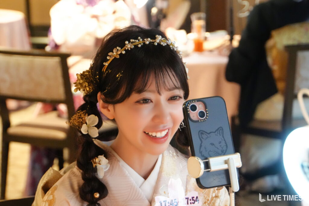 Woman in traditional attire with a floral headpiece taking a selfie using a smartphone.