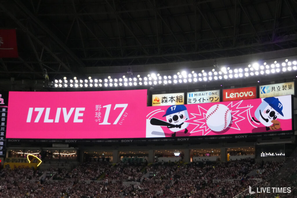 Inside a baseball stadium, a large pink banner shows '17 LIVE' above cartoon baseball mascots and sponsor signage.