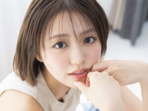Close-up of a young woman with brown hair, looking to the side, hands near her mouth in a thoughtful pose.