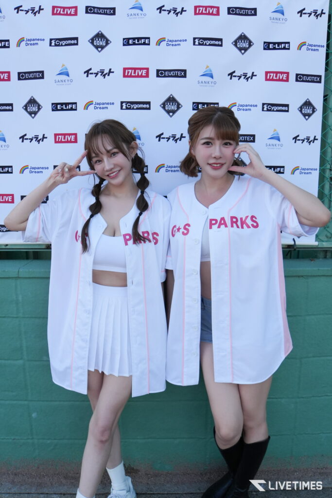 Two women in white Parks jerseys pose and smile in front of a sponsor backdrop with logos on a white wall.