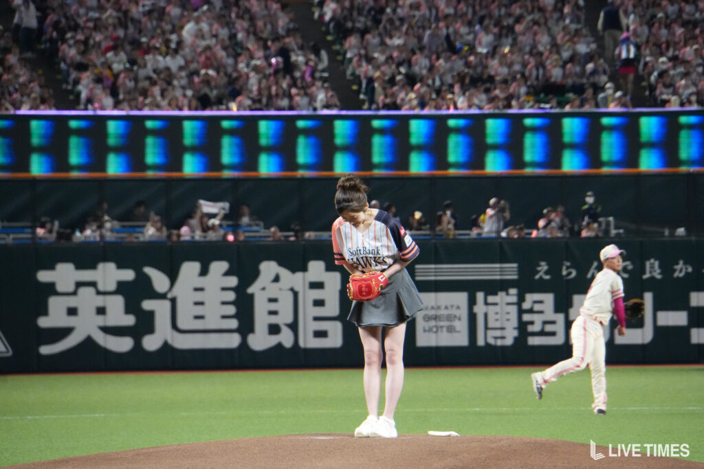 Pitcher on the mound preparing to pitch with a crowded stadium behind her.