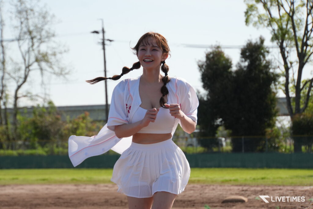 Smiling young woman running outdoors in a white outfit with braided hair on a sunny day.