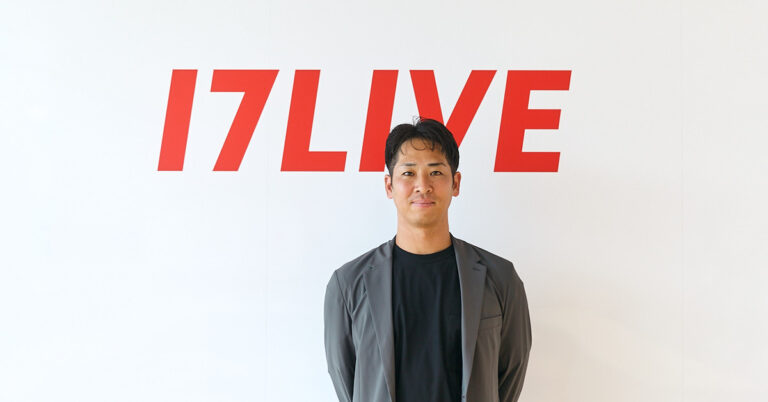 Man in a gray blazer stands before a white wall with a red 17LIVE logo behind him.