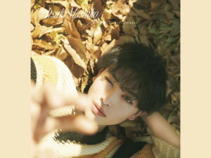 Close-up of a person resting among autumn leaves; beige knitwear visible and 'Atsuki Mashiko' text across the top.