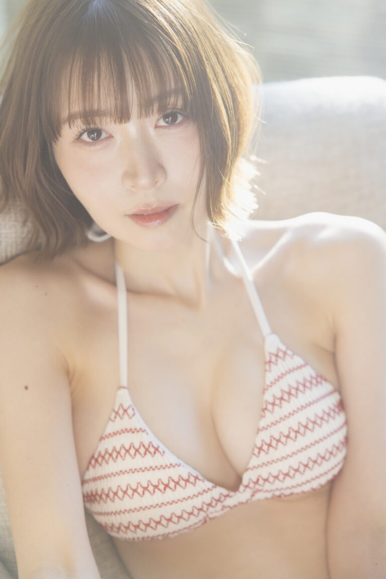 Close-up portrait of a woman in a red-and-white zigzag bikini top, bathed in warm sunlight.