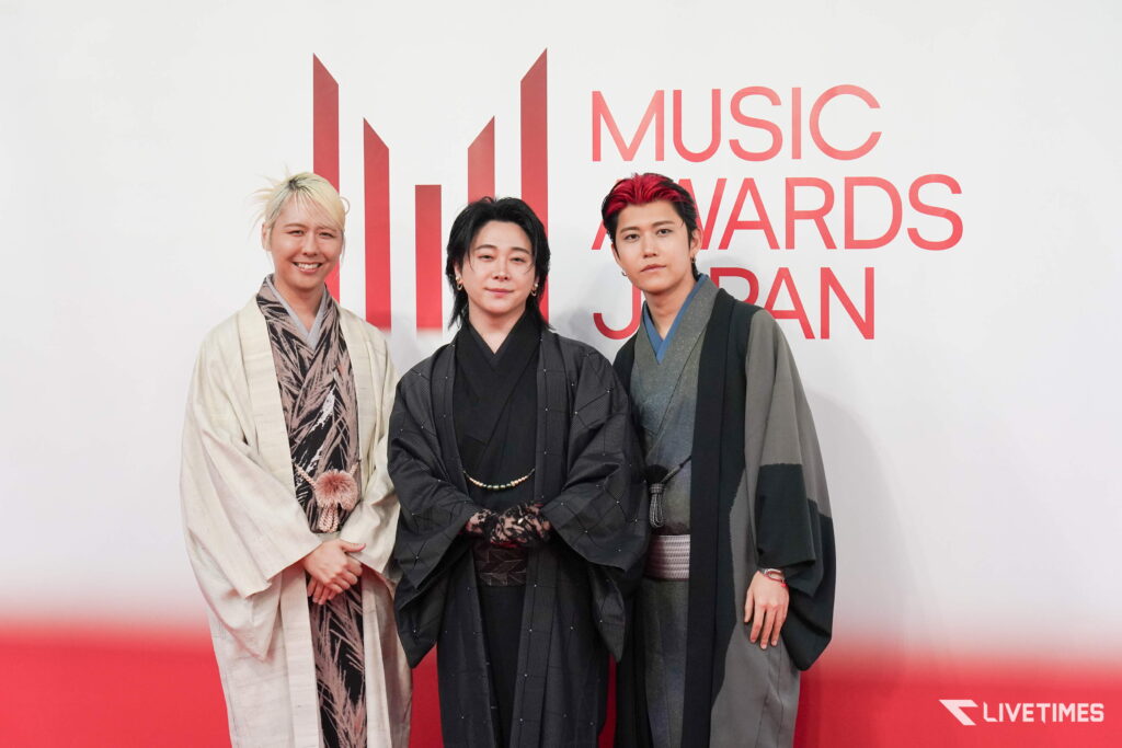 Three people in traditional Japanese garments pose on a red carpet at an event, Livetimes watermark visible bottom-right.