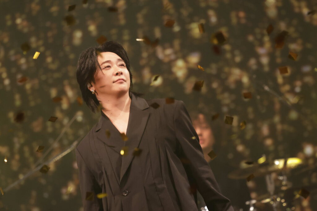 Performer on stage with a shower of gold confetti surrounding them