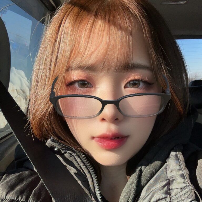 Young woman wearing black glasses in a sunlit car, with a brown bob and bangs hopeful expression.