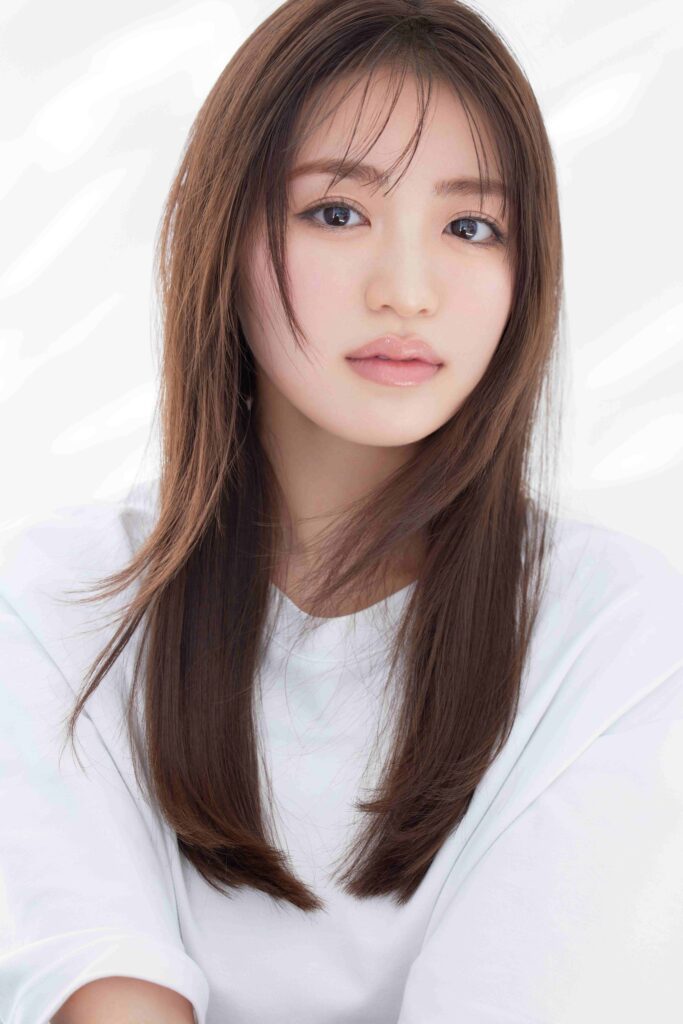 Close-up portrait of a young woman with long brown hair, light makeup, and a soft smile.