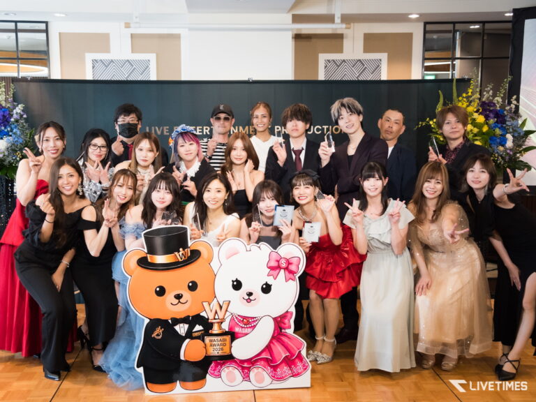 Group of people in formal outfits posing with awards on a stage, with large colorful cartoon bear cutouts in front.