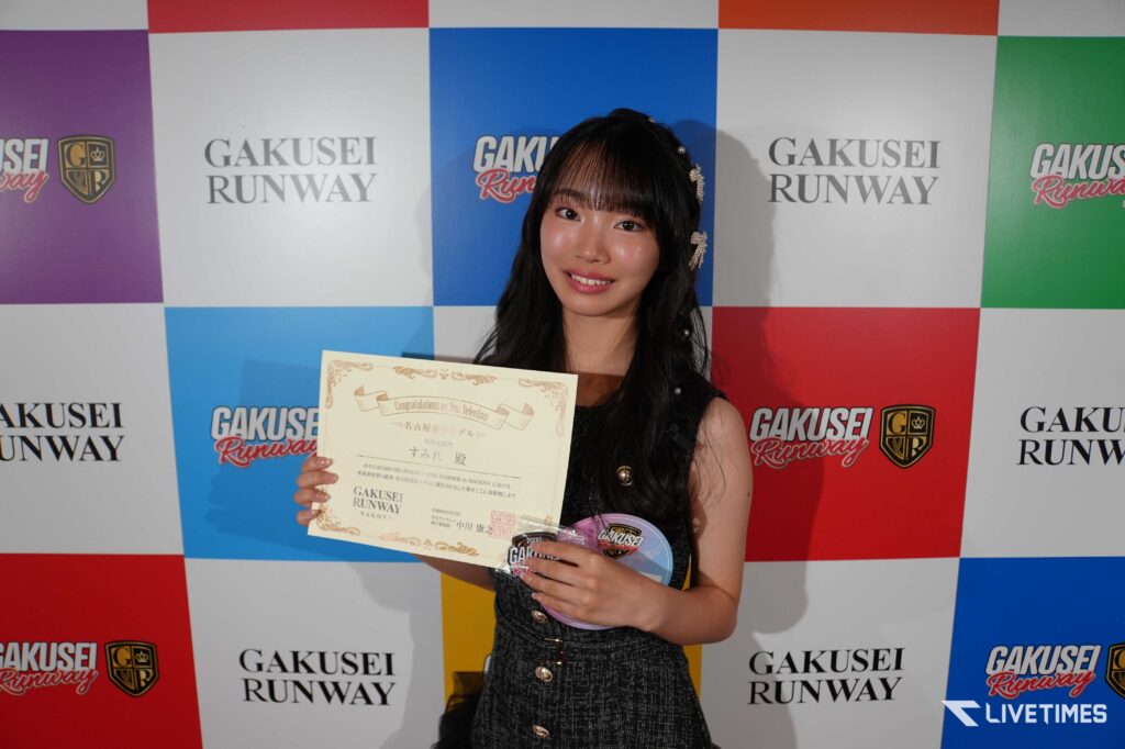 Young woman at a Gakusei Runway event, smiling and holding a certificate.
