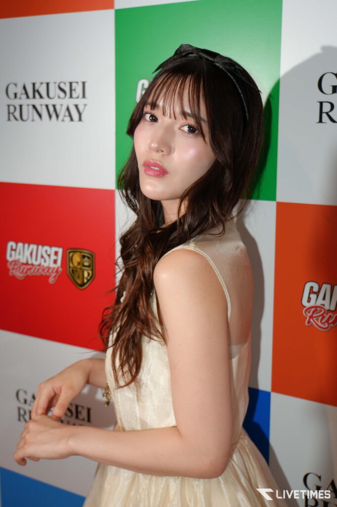 Model posing for photos at a backdrop with bold color blocks and 'Gakusei Runway' branding on white, green, red panels.