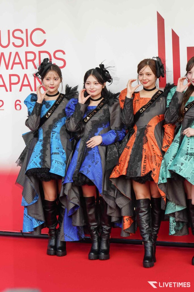 Four young women in colorful patterned outfits posing on a red-carpet at a music awards event.