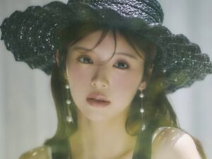 Portrait of a woman wearing a wide black hat and pearl earrings, with soft, dreamy lighting and natural makeup.