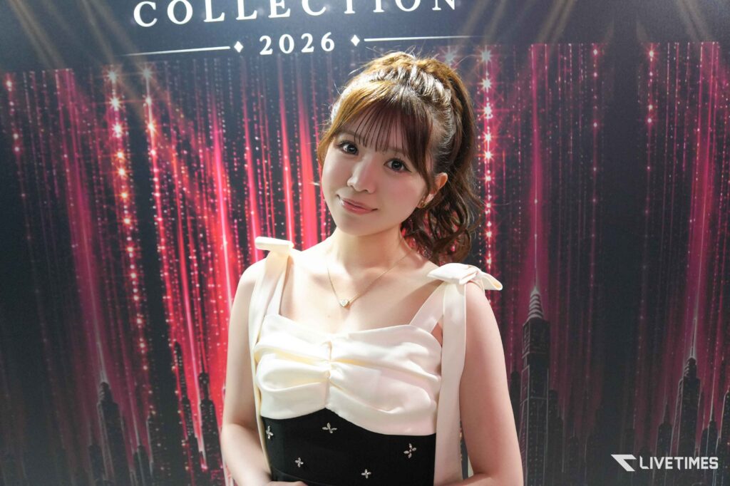 Young woman in a white dress posing against a red glittery backdrop that reads 'COLLECTION 2026'.