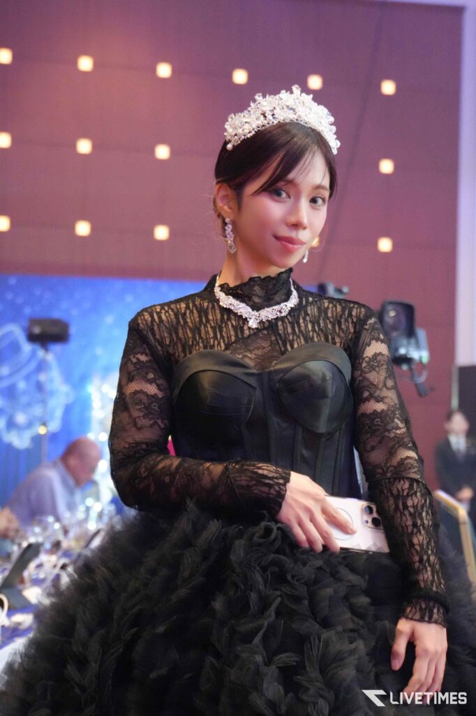 Young woman in a black lace gown with a jeweled tiara at a formal event