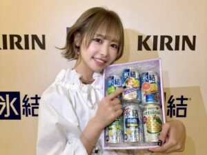 Smiling young woman holding a box of Kirin beverages at a promotional event.