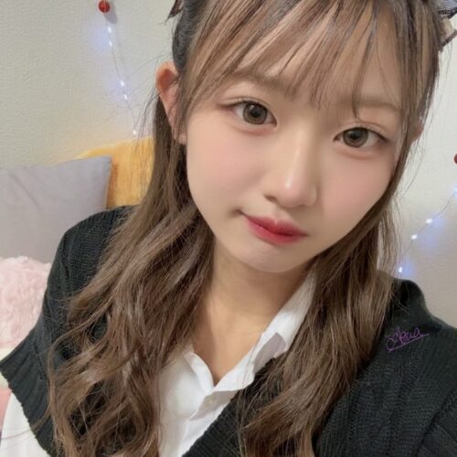 Young woman with long wavy hair and a plaid hair bow, indoors, soft makeup and a gentle smile.
